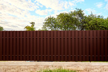 Seamless Brown Metal Profile Picket Fence. Side Wall High And Long. Opaque Surface Vertical Lines. Security. Private Property Fencing. Exterior. Neighbor Separation. Isolated Object. New Construction