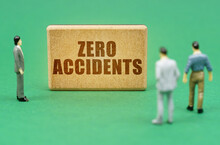 On The Green Surface Are Figures Of People And A Sign With The Inscription - Zero Accidents