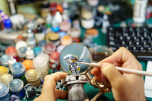 Man Painting Miniatures Of Board Game With Large Magnifying Glass.