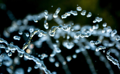 Drops of water splash blue water on a green background of nature, concept of freshness drink, watering the rain source of clean water, copy space