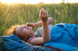 © Ольга Симонова - The girl is dissatisfied with scratching mosquito bites, child sleeps in a sleeping bag on the grass in a camping trip. Eco-friendly outdoor recreation, summer time. Sleep disturbance, repellent.