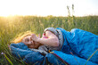 © Ольга Симонова - The girl is dissatisfied with scratching mosquito bites, child sleeps in a sleeping bag on the grass in a camping trip. Eco-friendly outdoor recreation, summer time. Sleep disturbance, repellent.