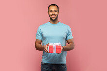 Romantic Young Black Guy Holding Gift Box, Smiling And Looking At Camera On Pink Studio Background