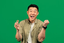 Joyful Asian Mature Man Showing Yes Gesture And Holding Golden Bitcoin In His Hand, Posing Over Green Background