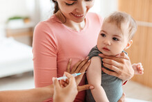 Vaccination Concept. Pediatrician Doctor Giving Vaccine Shot To Little Baby At Home, Making Injection For Infant Child