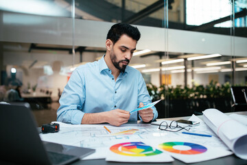 Wall Mural - Busy serious attractive millennial arab guy designer with beard works with color palettes at workplace