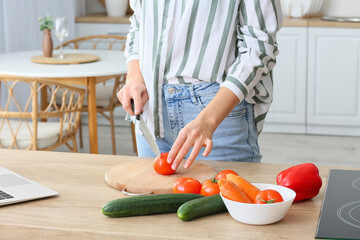 Wall Mural - Young woman cutting fresh tomato in kitchen, closeup