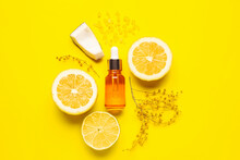 Bottle Of Natural Serum With Lemons, Coconut, Sea Salt And Flowers On Yellow Background