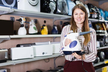 Wall Mural - Adult saleswoman offering steam cleaner in household appliances shop