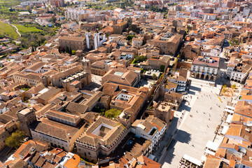 Scenic view from drone of historic quarter of Spanish city of Caceres overlooking brownish tiled roofs of old buildings around of main square on sunny spring day, Extremadura