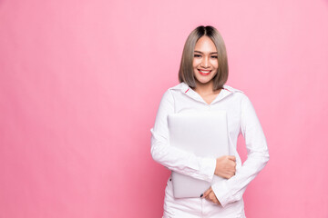 Young Asian smiling confident fun freelancer woman in white shirt hold going with closed laptop pc computer look aside isolated on pastel pink color background studio portrait