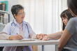 © KMPZZZ - Aged asian physician psychiatrist, general woman doctor holds the patient's hand to encourage the patient girl, child at the appointment at clinic, hospital. Health care, check up medical.