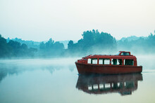 A Passenger Boat Floating In A Foggy Lake In The Morning 