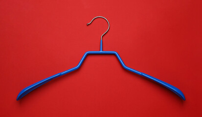 Wall Mural - Empty clothes hanger on red background, top view