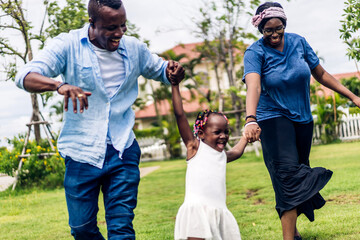 Wall Mural - Portrait of enjoy happy love black family african american father and mother with little african girl child smiling and play having fun moments good time in room at home