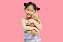 Asian Cute Little Asian Child Girl Hugging Teddy Bear Isolated On Pink Background.