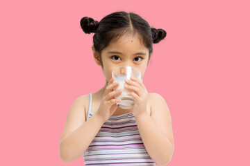 Wall Mural - Smiling little Asian girl drinking milk isolated on pink background.