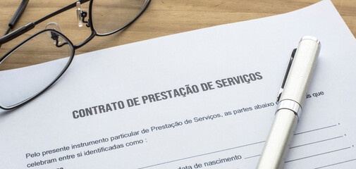 Wall Mural - A service provision contract in Portuguese language on the table. Agreement. Services. Contract and eyeglasses on the desk.