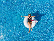 Aerial Top View From Above Of Woman On Unicorn Pool Float In Pool. Enjoying Summer Vacations During Quarantine.