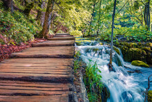 Wooden Footbridge In Plitvice National Park. Splendid Morning View Of Pure Water Waterfall. Fresh Green Scene Of Croatia, Europe. Beauty Of Nature Concept Background.