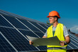 © RomanR - young engineer near solar panel and worker holding blueprint, photovoltaic