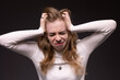 Young blond woman frightened, angry, crying and in defensive position.  Woman having headache, very sad and in mixed emotions. Terrified and frightened.  Black backgrond
