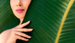 Green beauty portrait. Beautiful young woman posing against and behind fresh green tropical banana leaves. Organic cosmetic concept.