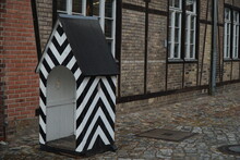 Empty Small White-black Sentry-box Near The Brick Wall