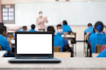 Computer on the table, blur image of the children classroom