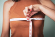 Slim woman measures her breast with a measuring tape