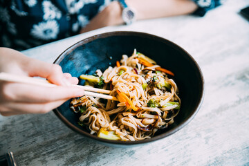 Woman eating asian noodles udon with pork in cafe. Asian noodles udon with pork close-up in a bowl on the table. 