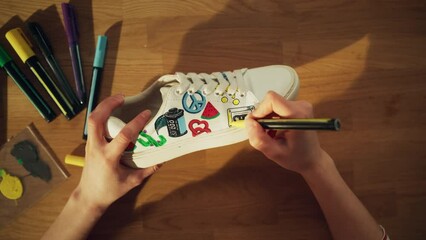 Aufkleber - Top View Shot: At Home Designer Sitting at the Wooden Desk and Applying Coloured Pictures at the Shoe. Hand Made Footwear and Creative Process Concept. Close Up