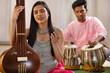 © IndiaPix - Close-up view of a young woman playing Tanpura and a man accompanying her on tabla