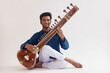 © IndiaPix - Portrait of cheerful young man playing sitar