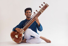 Portrait Of Cheerful Young Man Playing Sitar