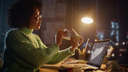 Poster - Millennial Designer Workspace: Brazilian Female Artist Sitting at the Desk and Applying her Own Designs on the Custom Shoe. Woman Working Late at Evening. People with Fresh Ideas Concept