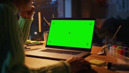 Poster - Close Up View of Brasilian Female Designer Working at Laptop with Green Screen. Woman Using Computer Mouse while Creating New Project. Freelance and Millennial People Concept. Over the Shoulder
