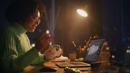 Poster - Black Footwear Designer Looking at Sneakers and Checking with 3d Model at Laptop while Drawing on it. Latin Woman Preparing Hand Made Footwear at Evening. Art and Small Business Concept