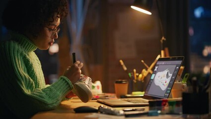 Poster - Black Female Artist Puts Unique Designs on Shoe Comparing with 3D Model on the Laptop Screen. Brasilian Woman Drawing at Evening. Hand Made and Craft Concept. Establishing Shot