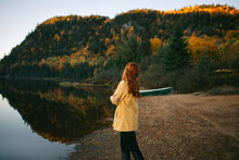Female Tourist Admiring Lush Autumn Trees Surrounding Lake In Nature