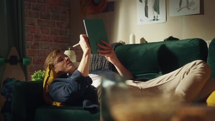 Fototapete - Focused Male Designer Work on Digital Tablet, while Resting at the Couch in Creative Office Environment. New Generation Young Person Drawing, Writing, Creating New Things Concept. Slow Motion