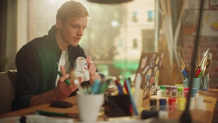 Poster - Up-and-Coming Designer Completes Work on a Unique Pair of Sneakers. Smiled Man Checks Result of Work with the Project on his Laptop. Breakthrough in Eco Design Concept