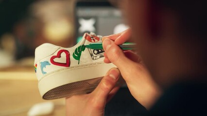 Poster - Male Artist Working on Colourful Design of Footwear in Loft Showroom. Fashion Designer Customising Pair of Shoes. Post Production Concept. Over the Shoulder Close-up