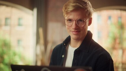 Aufkleber - Portrait of a Handsome Man Working from Home on Laptop Computer in Stylish Loft Apartment. Creative Male Browsing Internet and Looking at the Camera with Smile. Modern Occupation Concept