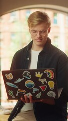 Aufkleber - Vertical Portrait of a Handsome Man Working from Home on Laptop Computer. Creative Male Browsing Internet and Looking at the Camera with Smile. Modern Occupation Concept. Slow Motion