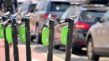 Row Of Electric Scooters For Sharing On The Street In Cluj, Romania. Cars On The Background