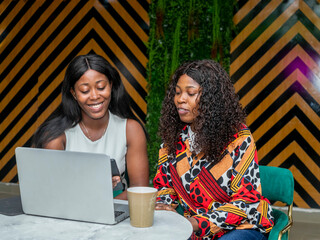 two young african female friends using modern technology device reading online news from the web checking news feed internet