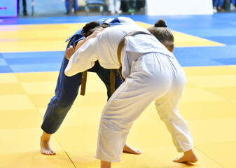 Two Girls judoka in kimono compete on the tatami 