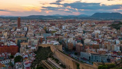Wall Mural - Alicante, Spain. Aerial view of Alicante, Spain in the evening. It is a popular summer resort of Costa Blanca. Time-lapse, illumination at sunset. Mountains at the background, panning video