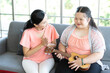 mother teaching and encourage to a girl with down syndrome singing and playing ukulele or small guitar on sofa